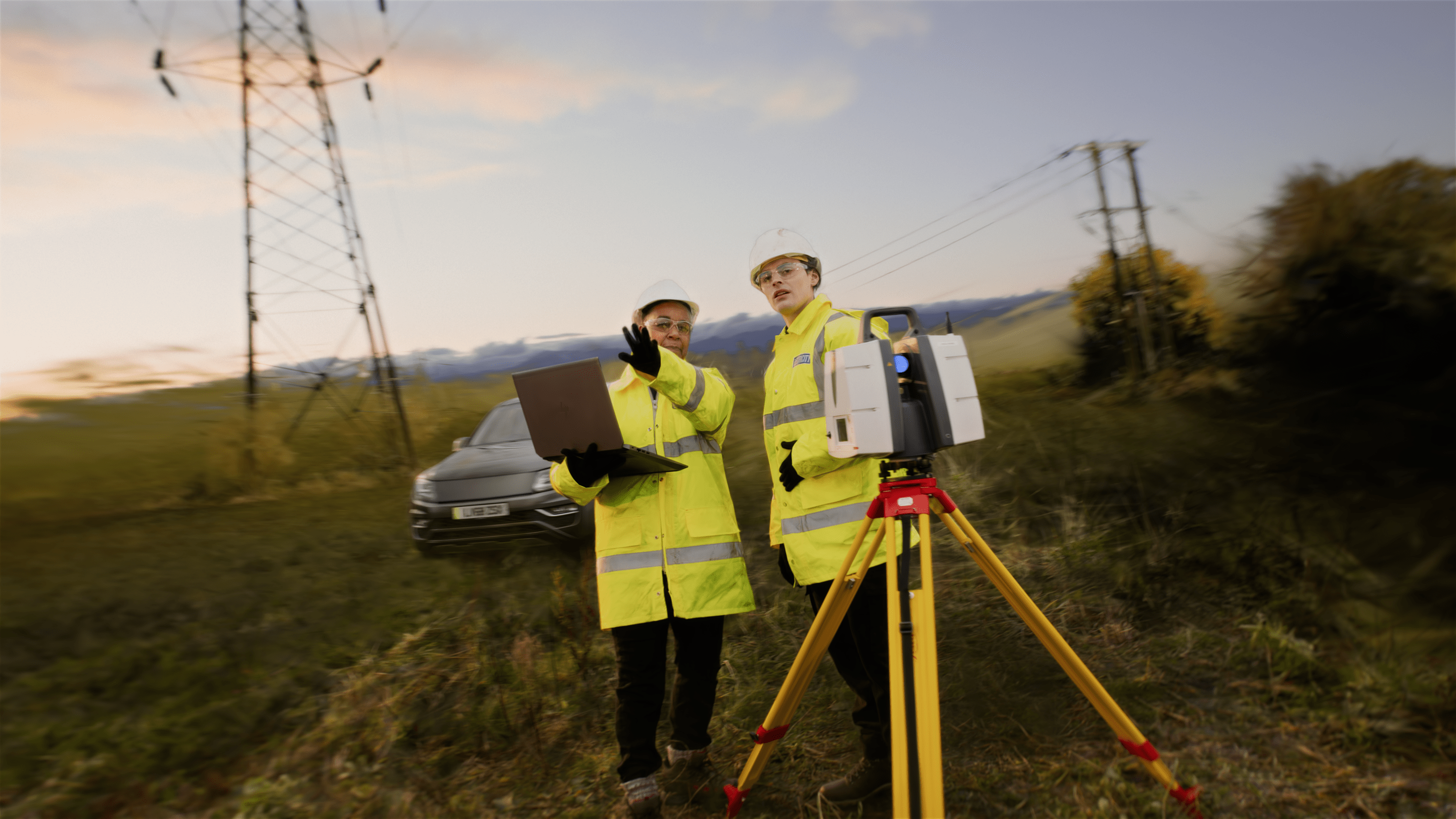 Operatives measuring using large equipment whilst wearing high-vis jackets.