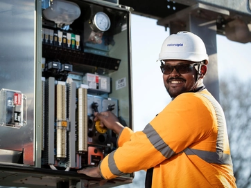 Man working on technical equipment whilst smiling.