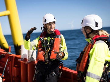 Two operatives on a boat out at sea discussing their approach.