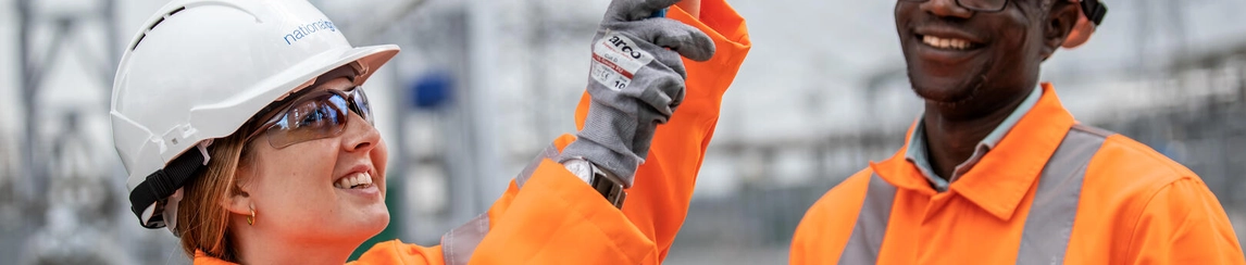 Man and woman wearing hi-vis jackets, working technical machinery.