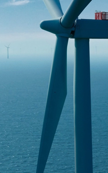 White large offshore wind turbines in the spinning in the ocean.